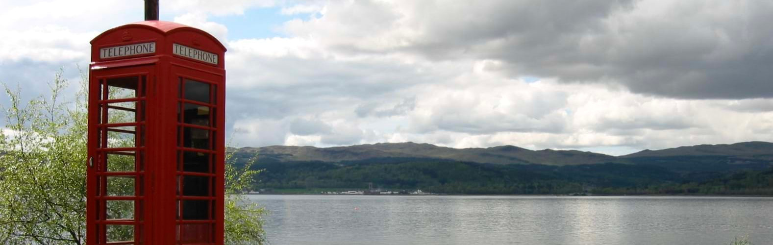 Red Telephone Booth with Lake and Hills in Background